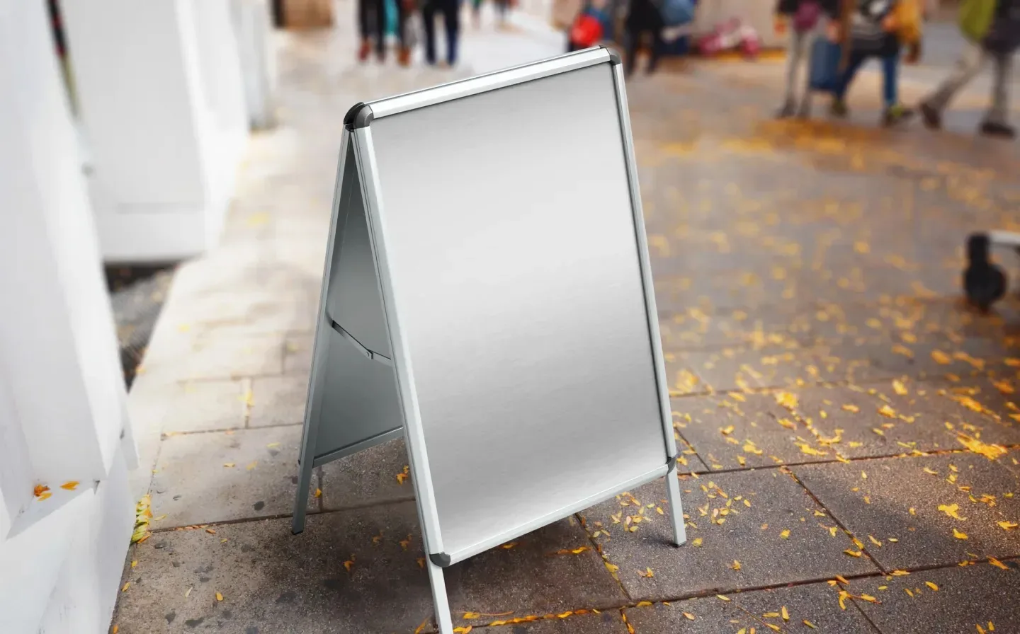A blank a frame sign positioned on a wet autumn floor in front of a building
