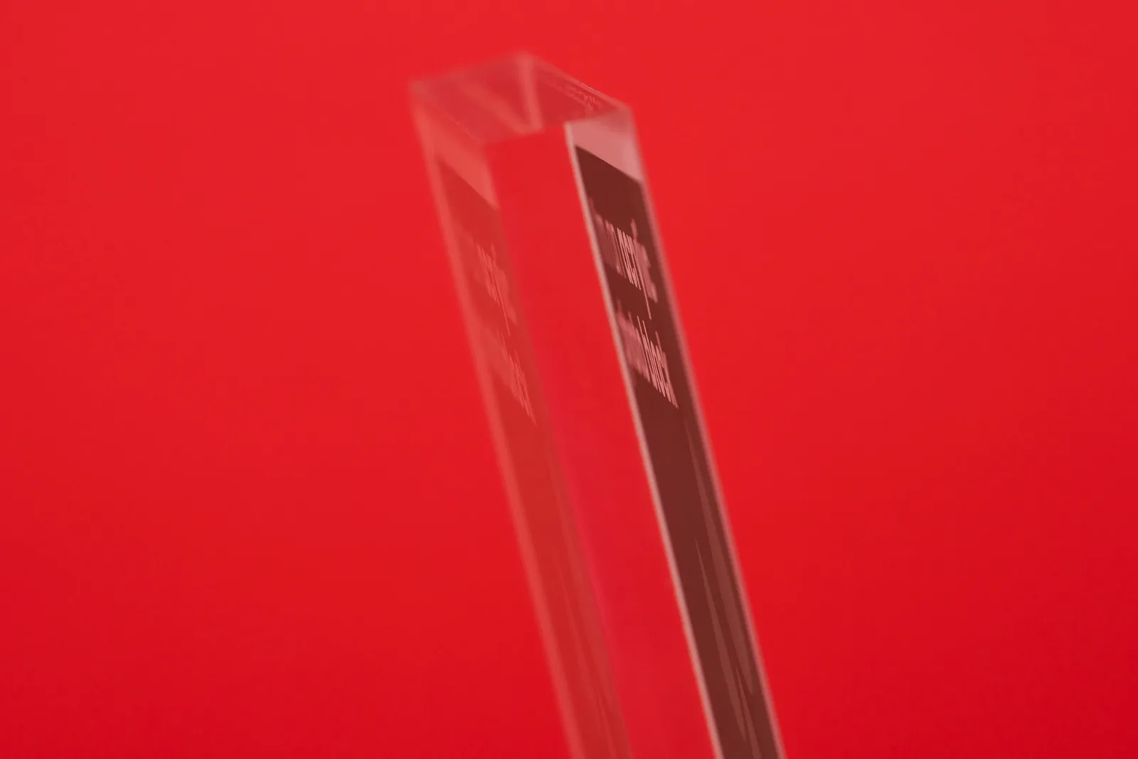 side close up of a clear acrylic photo block showing the green print reflection on a bright red background
