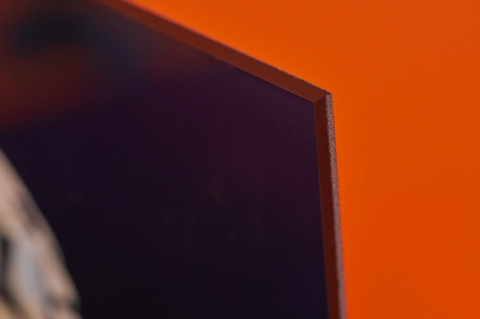 close up corner of a black printed acrylic print on a bright orange background