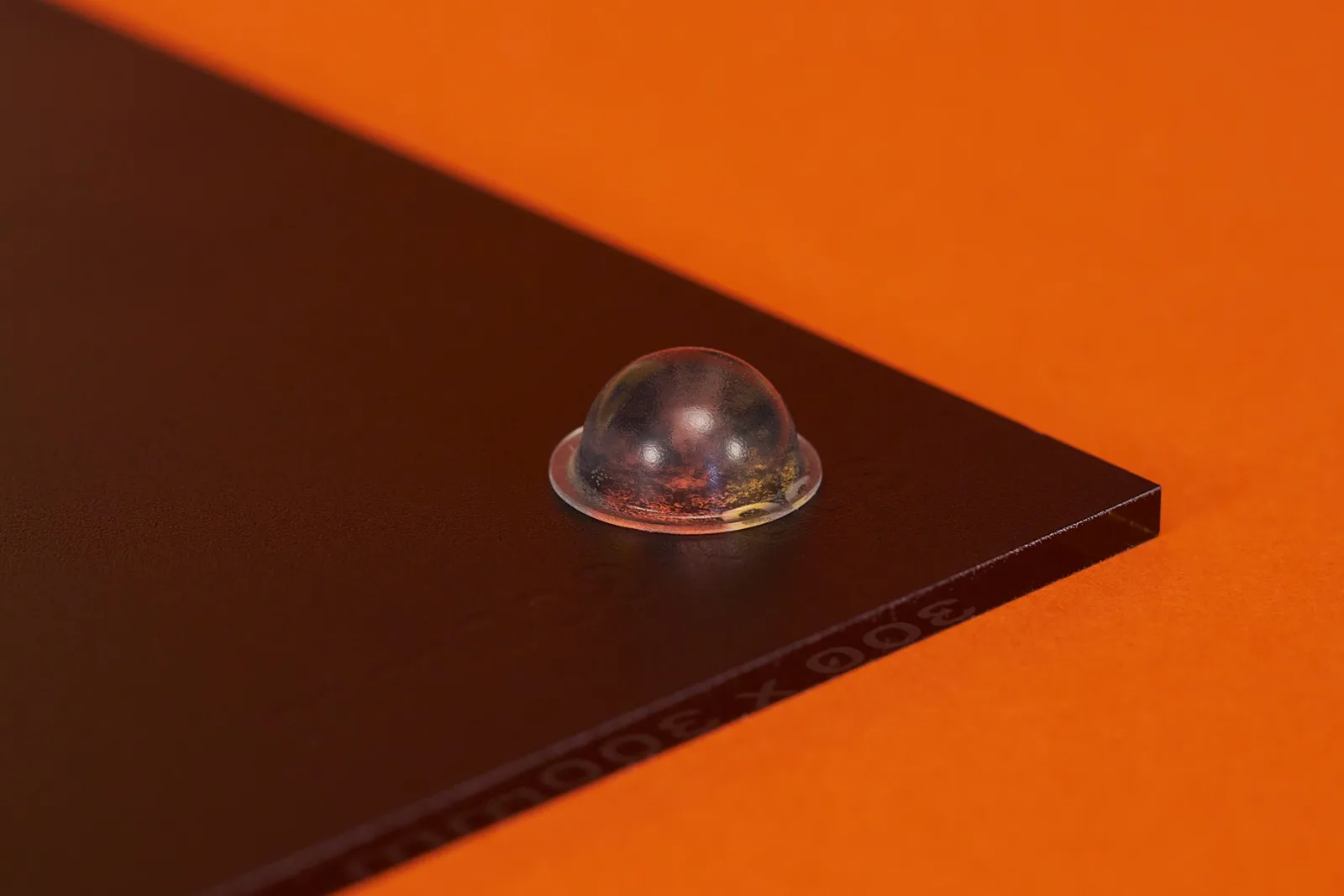 close up of a black acrylic print showing detail of rubber standoff on bright orange background