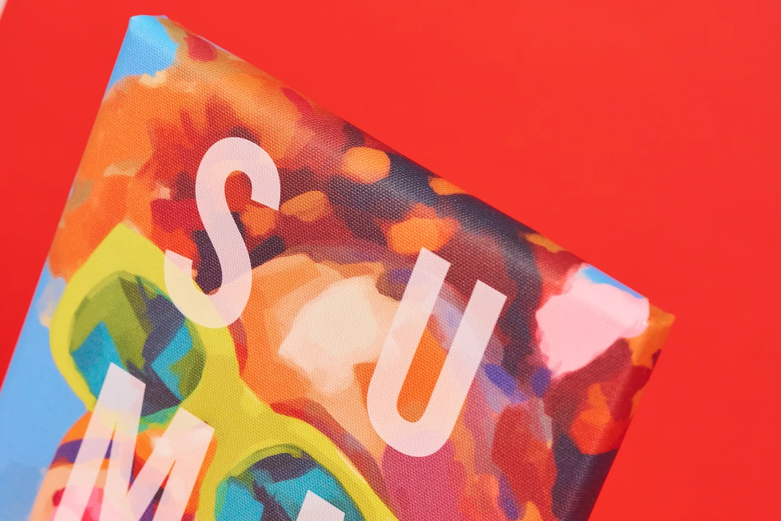 close up detail of a canvas print with letters 's, u, m' on bright red background