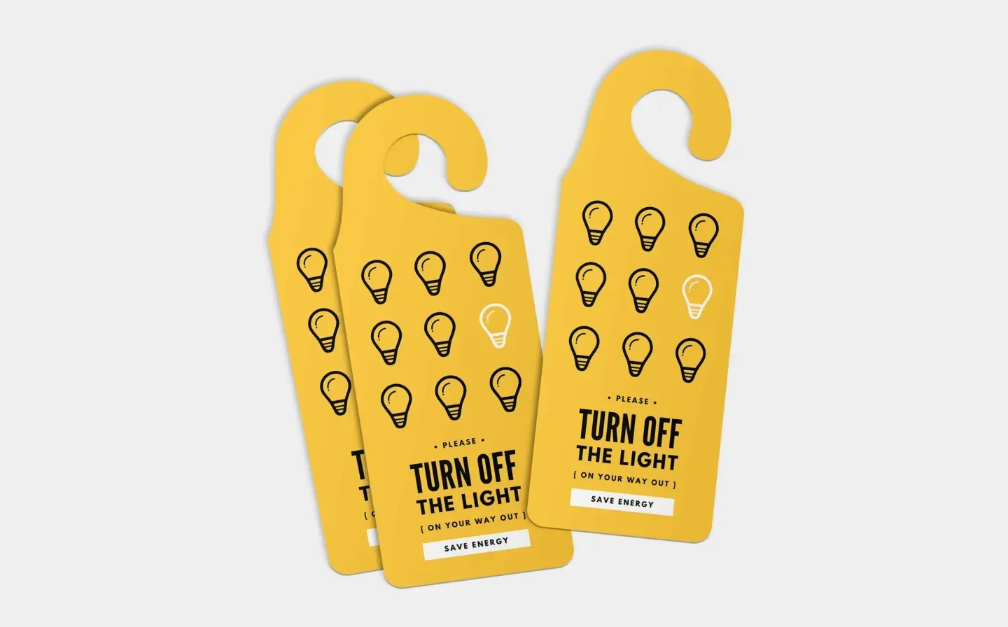 A stack of three yellow door hanger signs displaying the message "Turn Off The Light"
