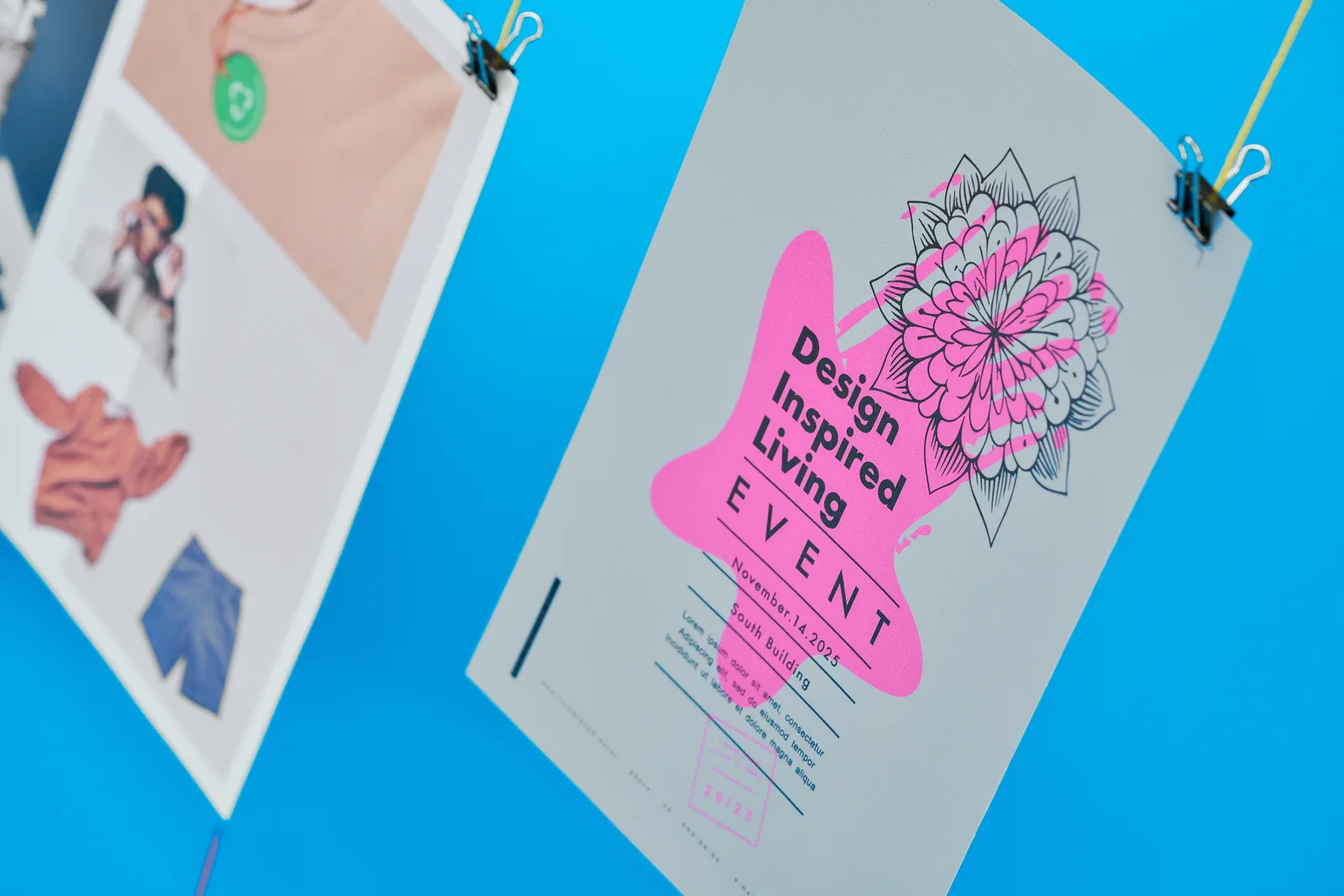 close up of a a4 portrait poster with text 'design inspired living event' hanging from yellow string with part of an a3 poster to the left on a bright blue background