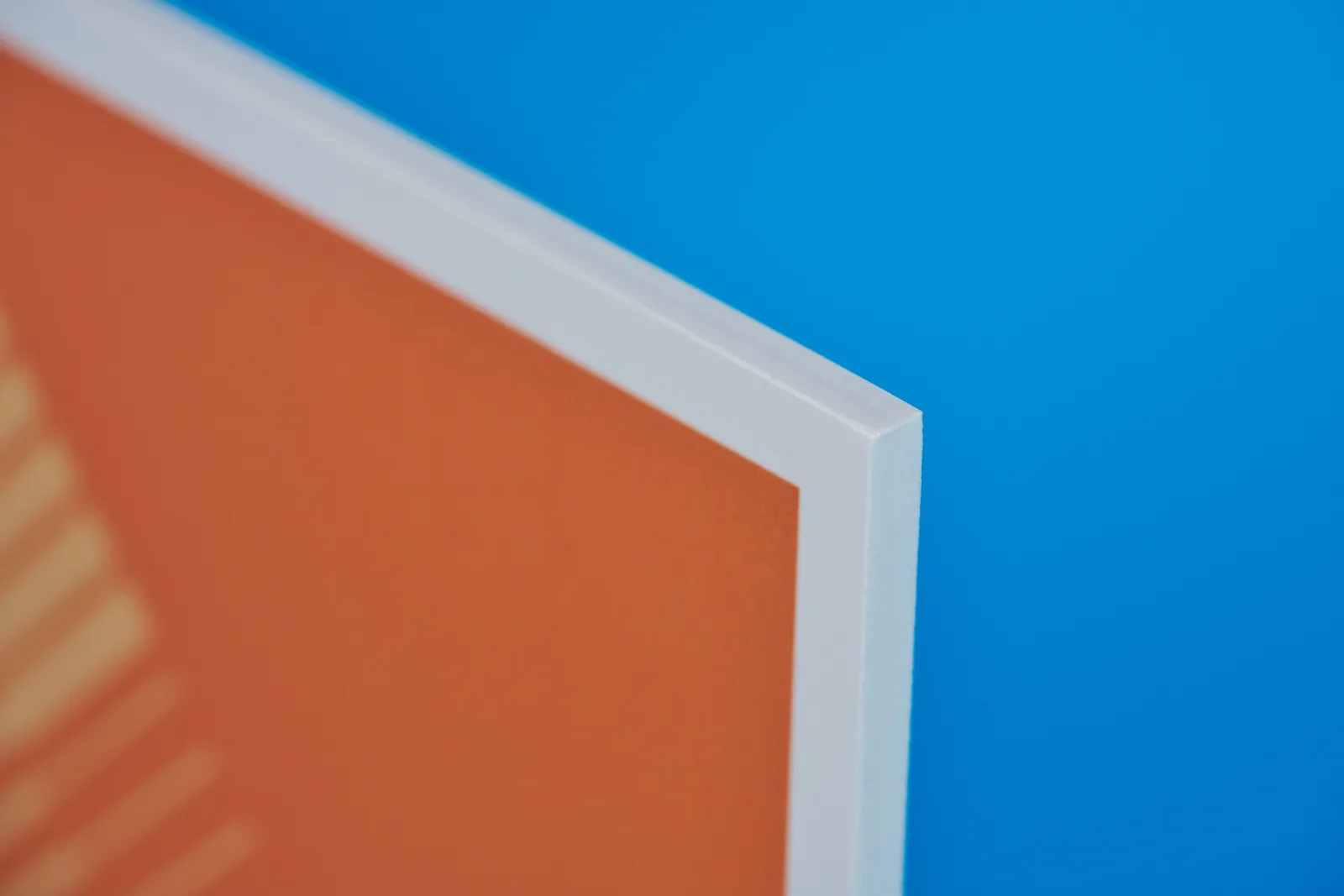 Close up of a orange printed foamex sign showing detail of material on a bright blue background