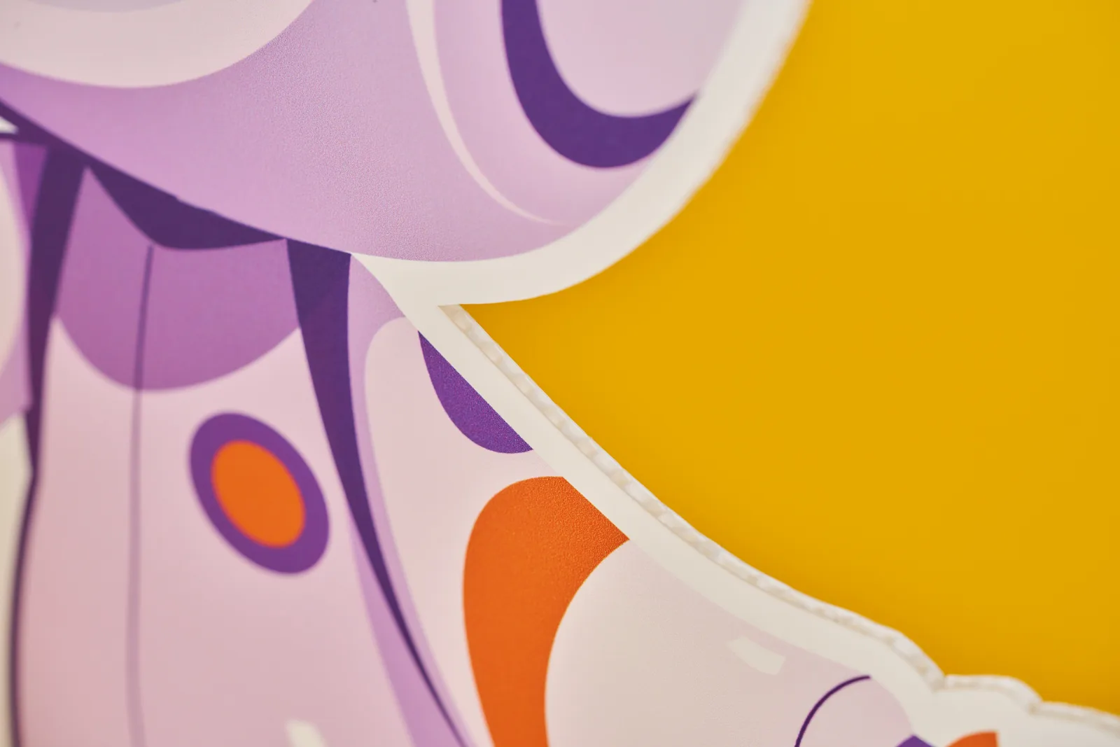 close up of a life size cutout of purple and orange cartoon spaceman's arm on a bright yellow background