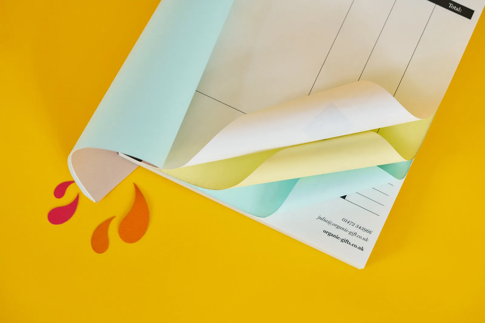 a4 ncr book showing white top sheet and yellow and blue duplicate sheets on a bright yellow background with red and orange paper ink splats
