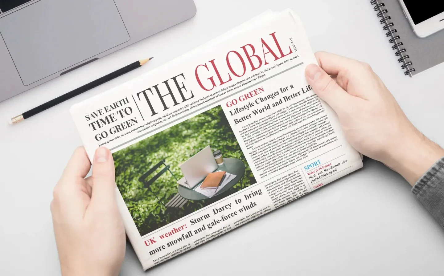 A workspace with a newspaper, laptop, and coffee cup
