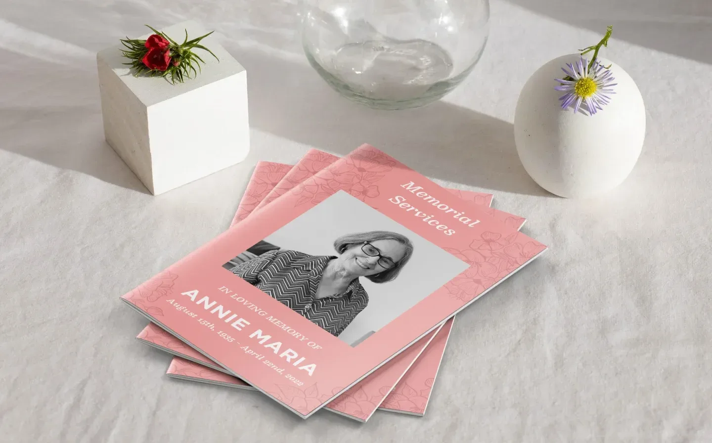  A pink order of service book rests on a table beside a flower vase