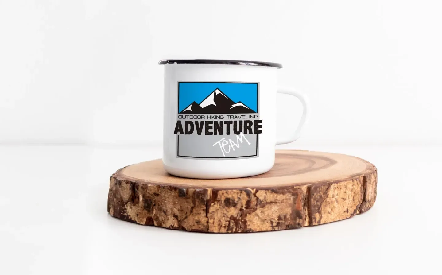 A white enamel mug featuring the word "Adventure" printed on its surface, displayed on a wooden plank on a plain background