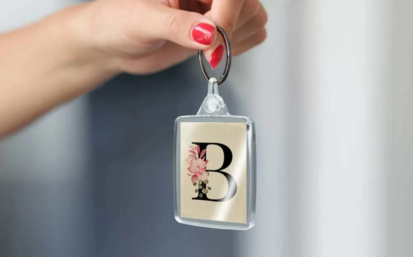 A person is holding a keyring featuring a prominent letter 'b' attached to it