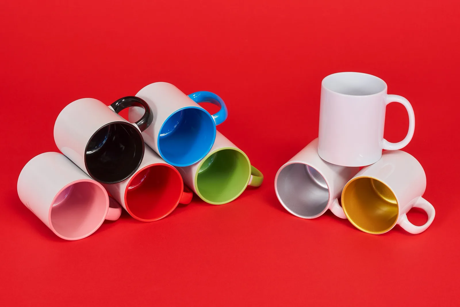 8 blank mugs, black, pink, blue, red, green, white, silver and gold showing all colours available on a bright red background