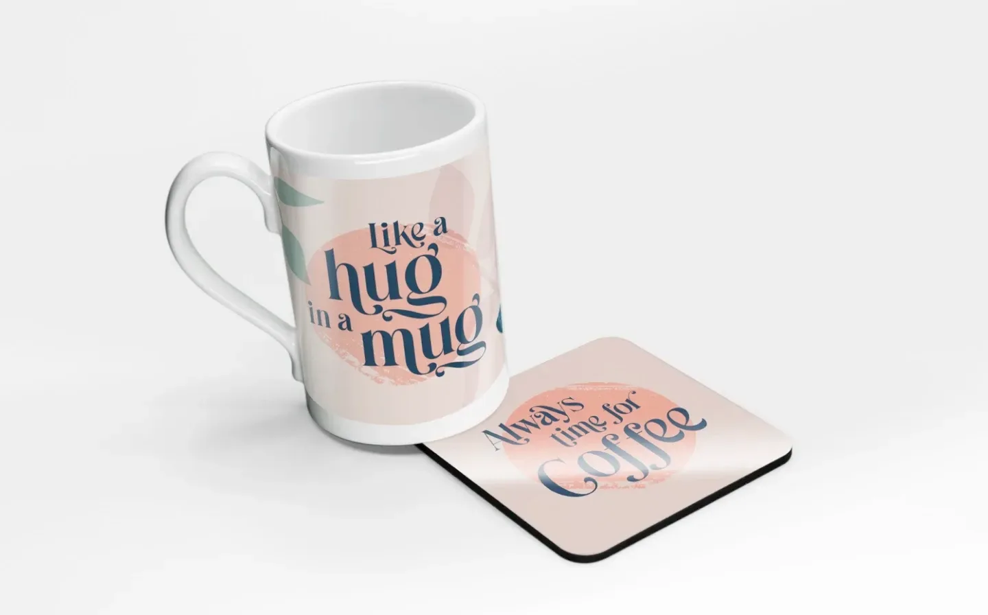 A porcelain mug placed on a coaster, with lettering saying "Like A Hug In A Mug", displayed on a plain background