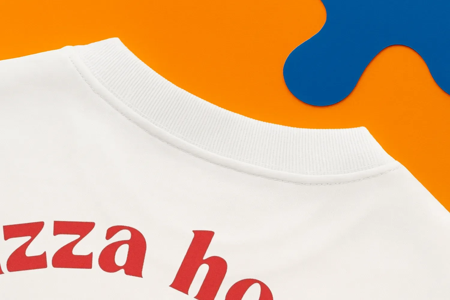 Close-up of a white shirt with red text on an orange surface and blue abstract shapes.