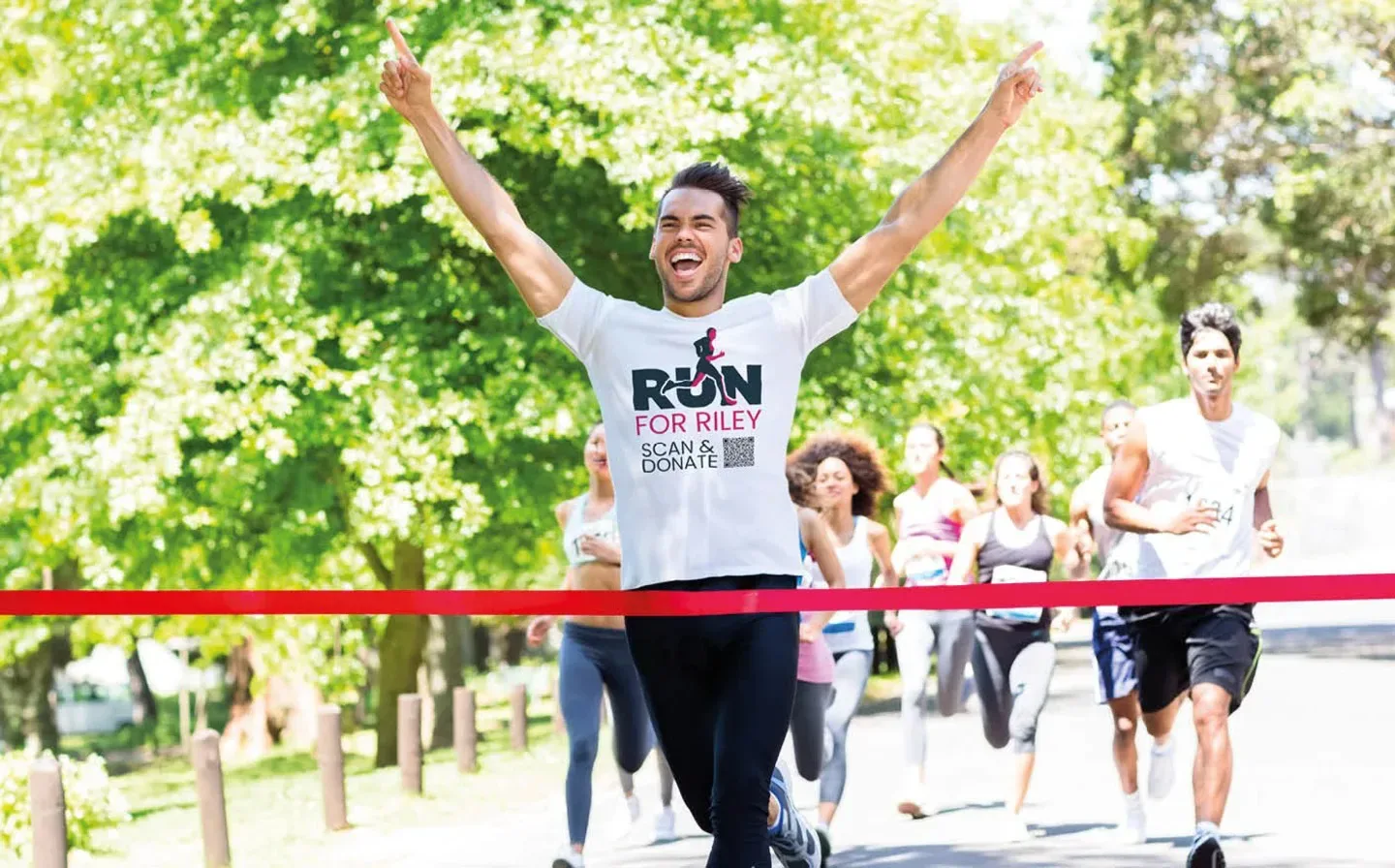 A man in a custom t-shirt triumphantly crosses the finish line of a marathon