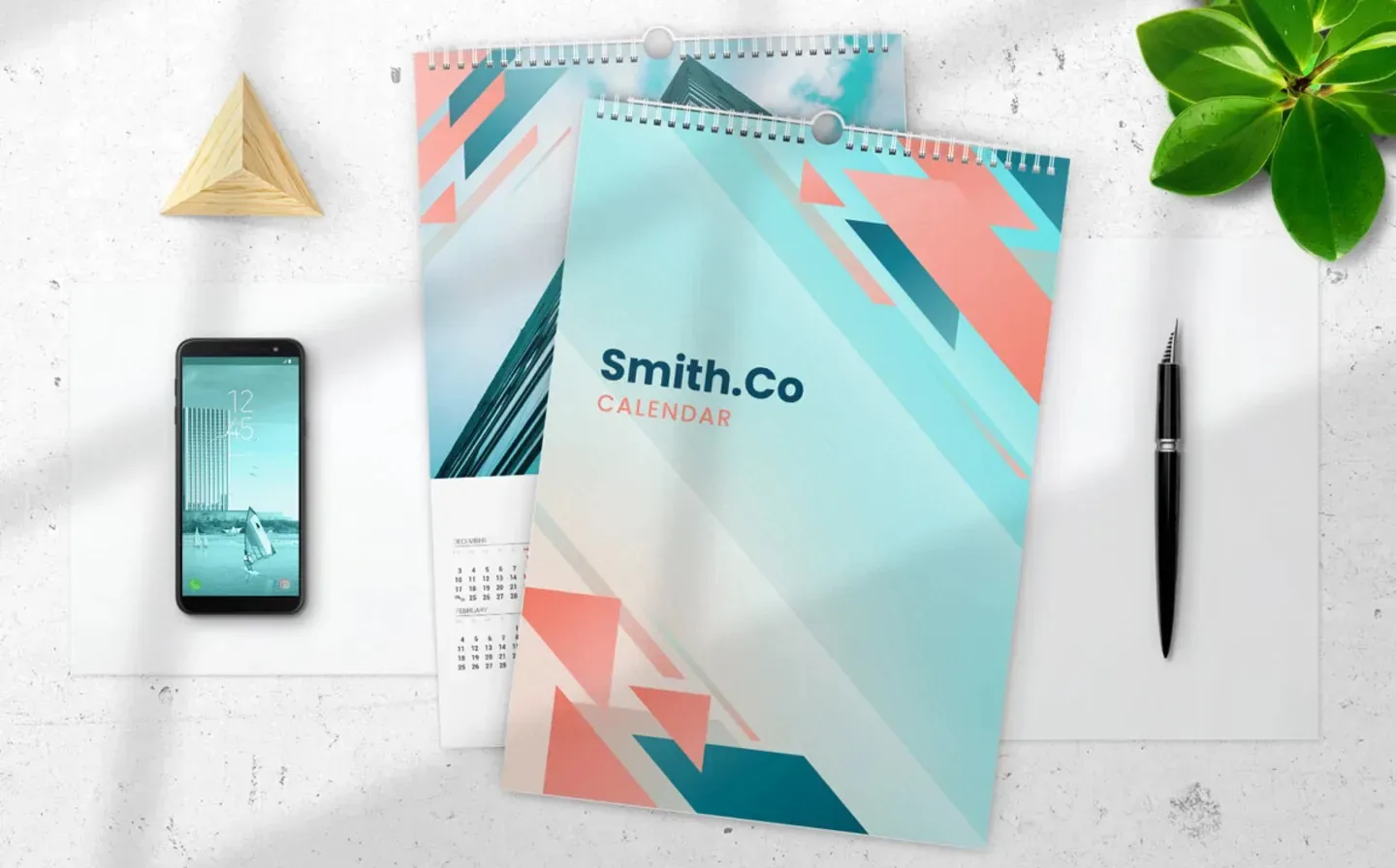A calendar displayed on a desk alongside a pen and a phone