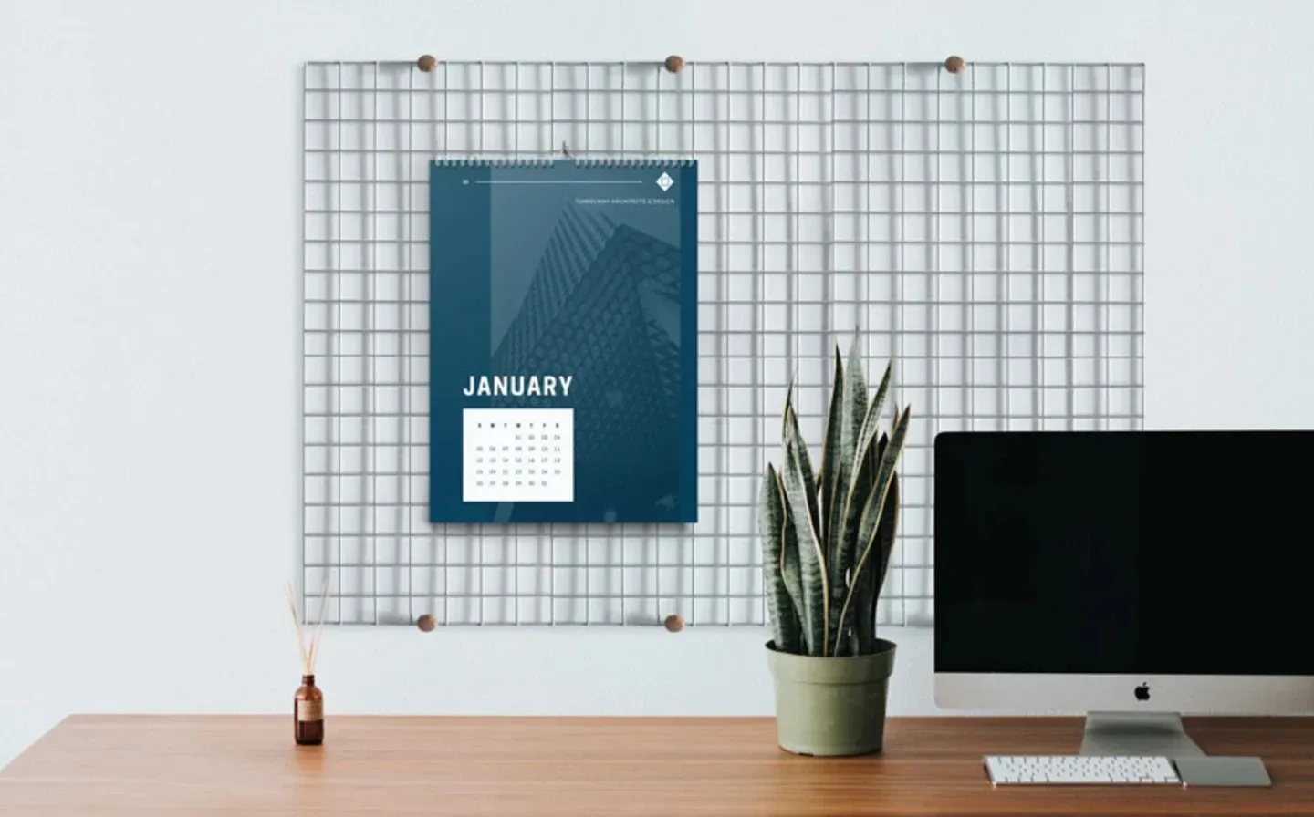 A desk featuring a computer, a plant, and a calendar