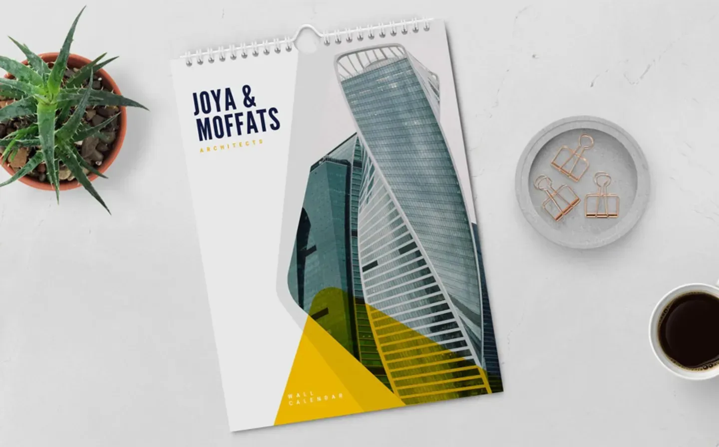 A calendar displayed on a desk alongside a coffee cup and a small plant