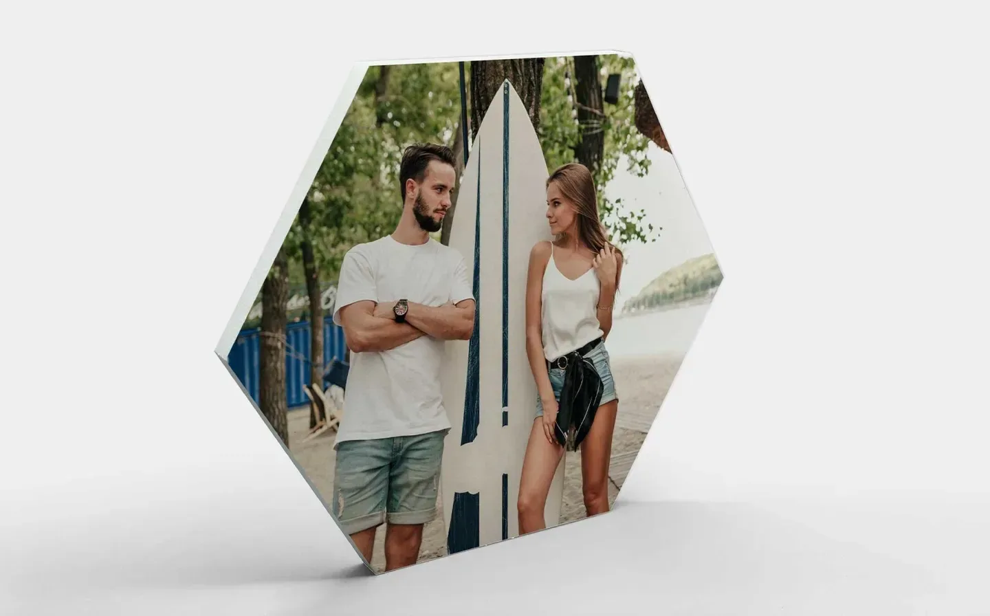 A close-up of a hexagon-shaped photo tile of a couple standing next to a surfboard