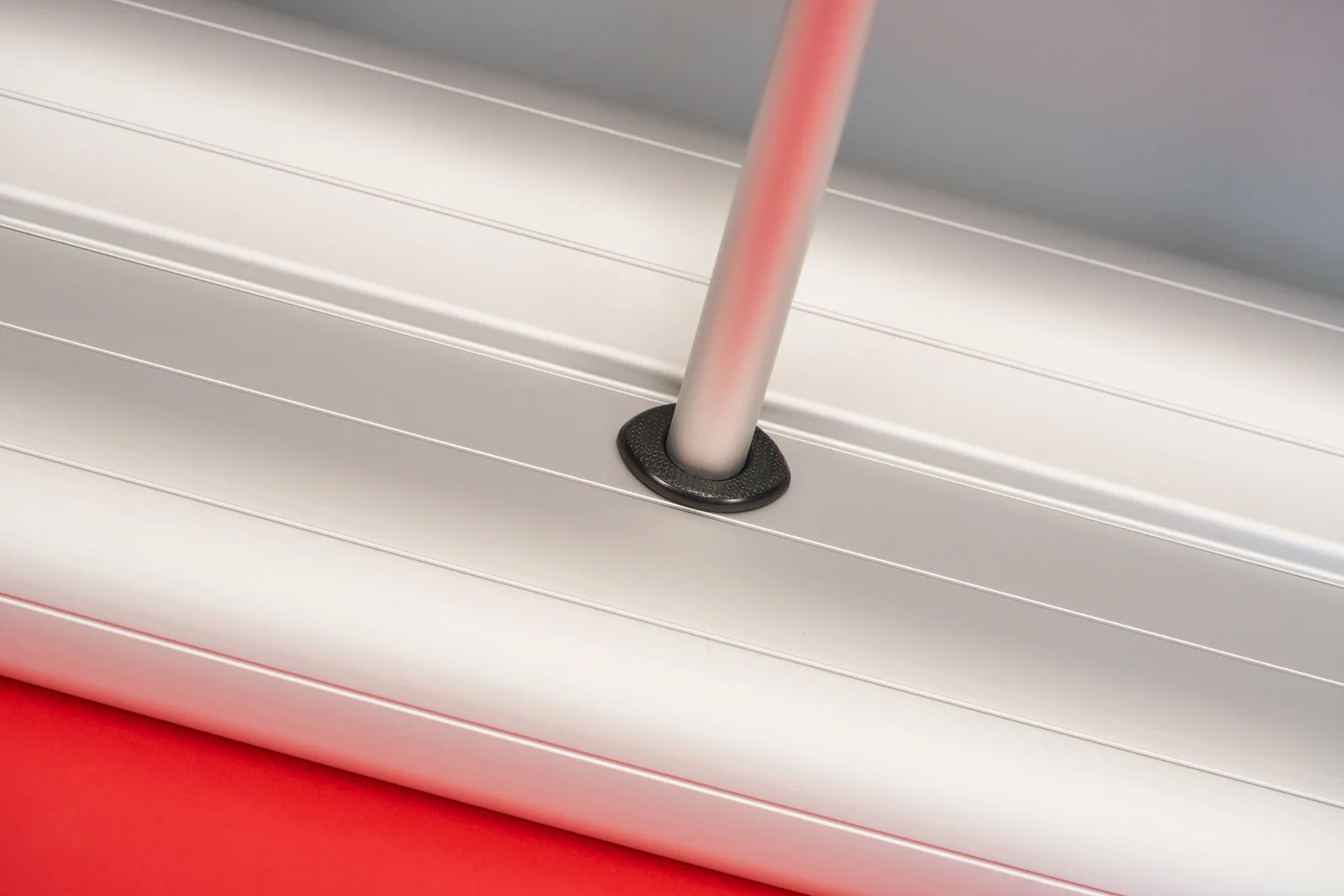 close up detail of a silver premium roller banner cassette showing support pole connected on a bright red background 
