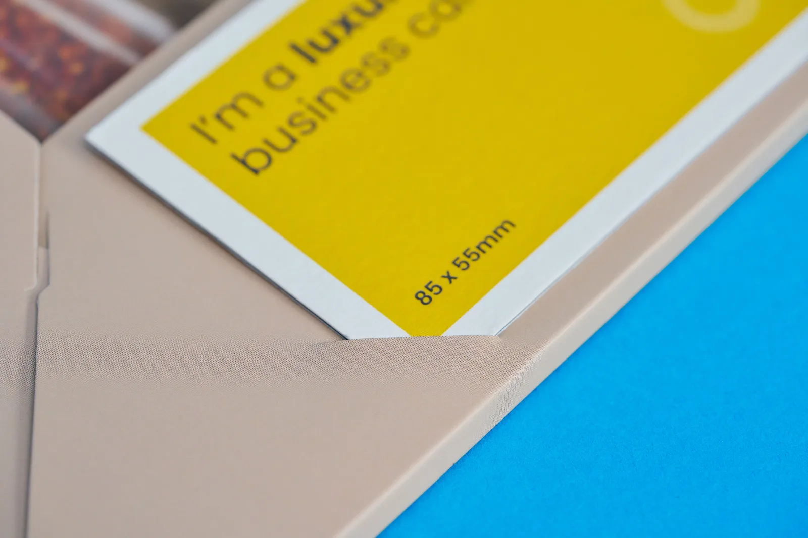 bright yellow business card insite slits of a cream interlocking presentation folder on a bright blue background