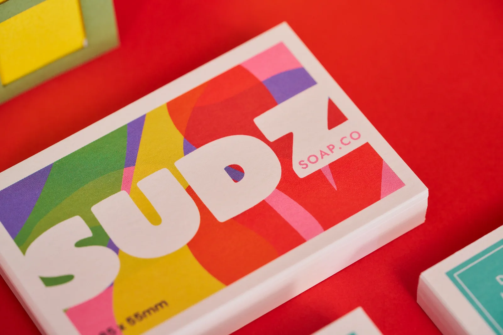 pile of recycled business cards with text 'sudz soap co' on bright red background