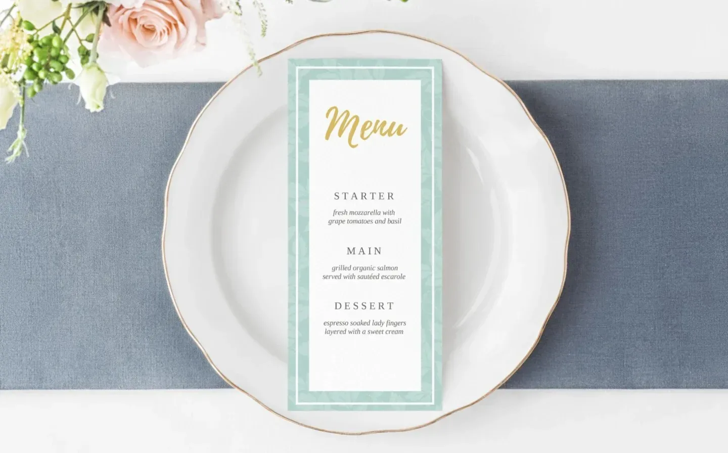 A mint green and gold wedding menu card elegantly placed on a decorative plate