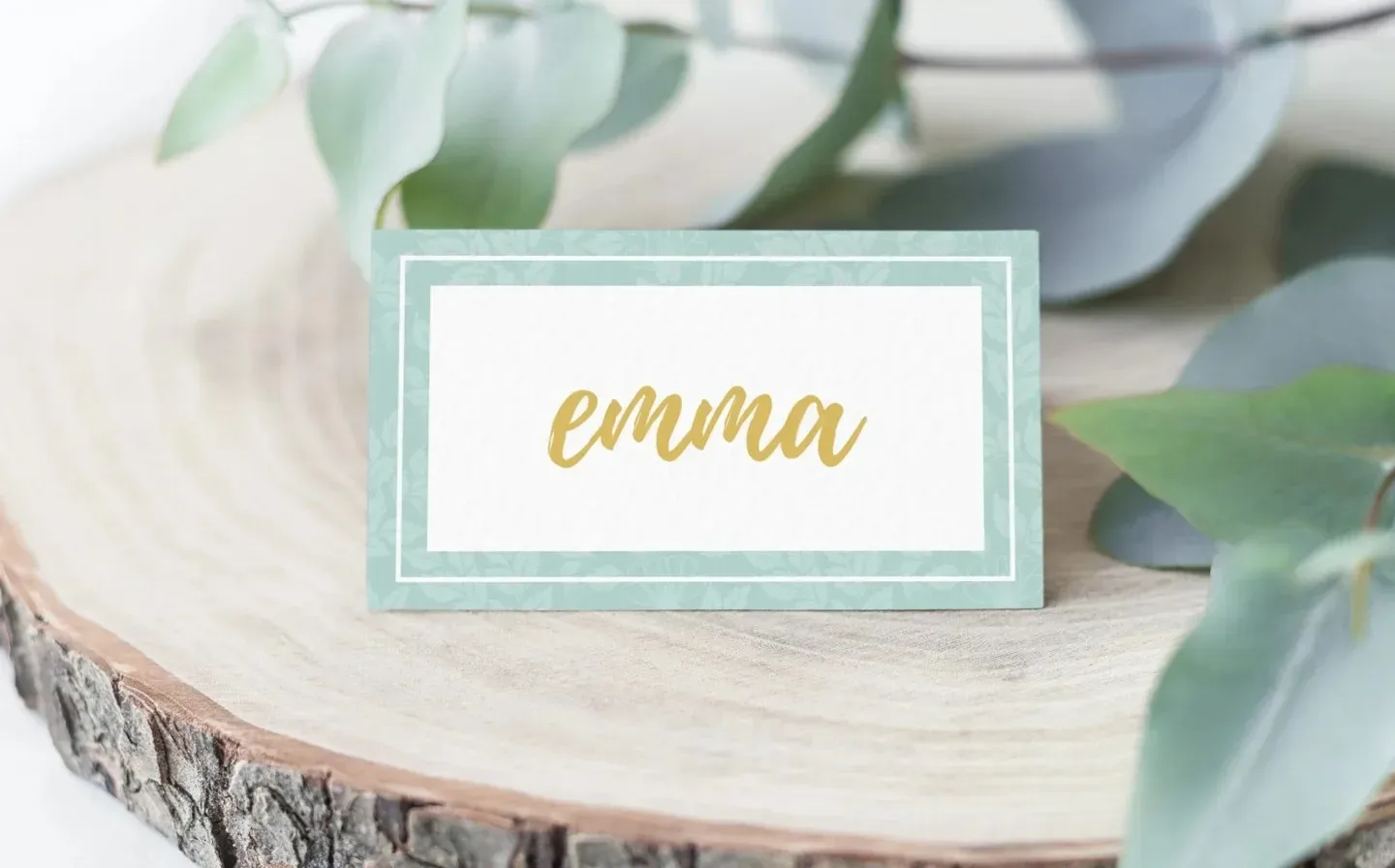 A mint green place card for a wedding, positioned on a table, indicating the name of a guest