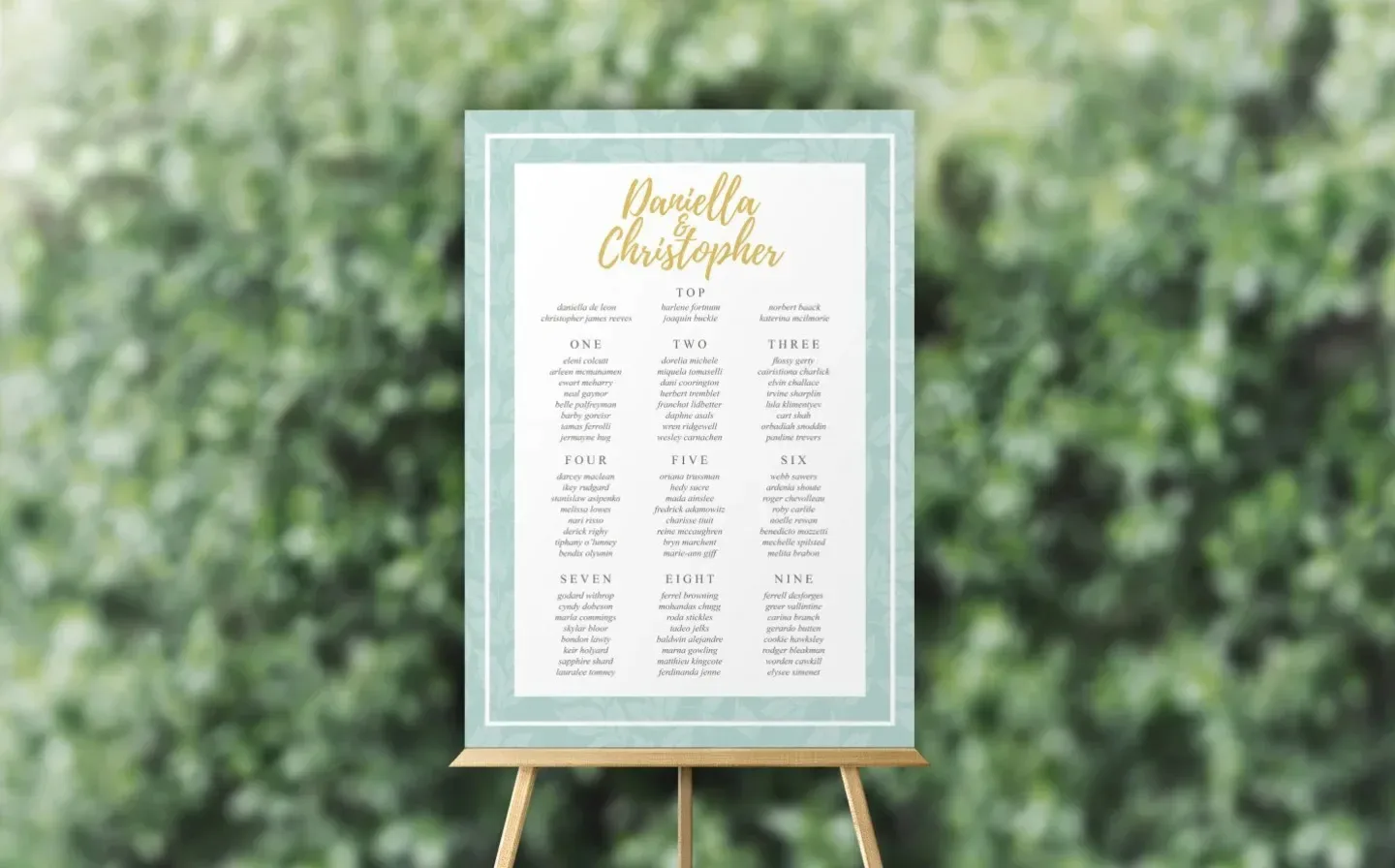 Elegant wedding seating chart in aqua and gold displayed at an outdoor reception, guiding guests to their tables